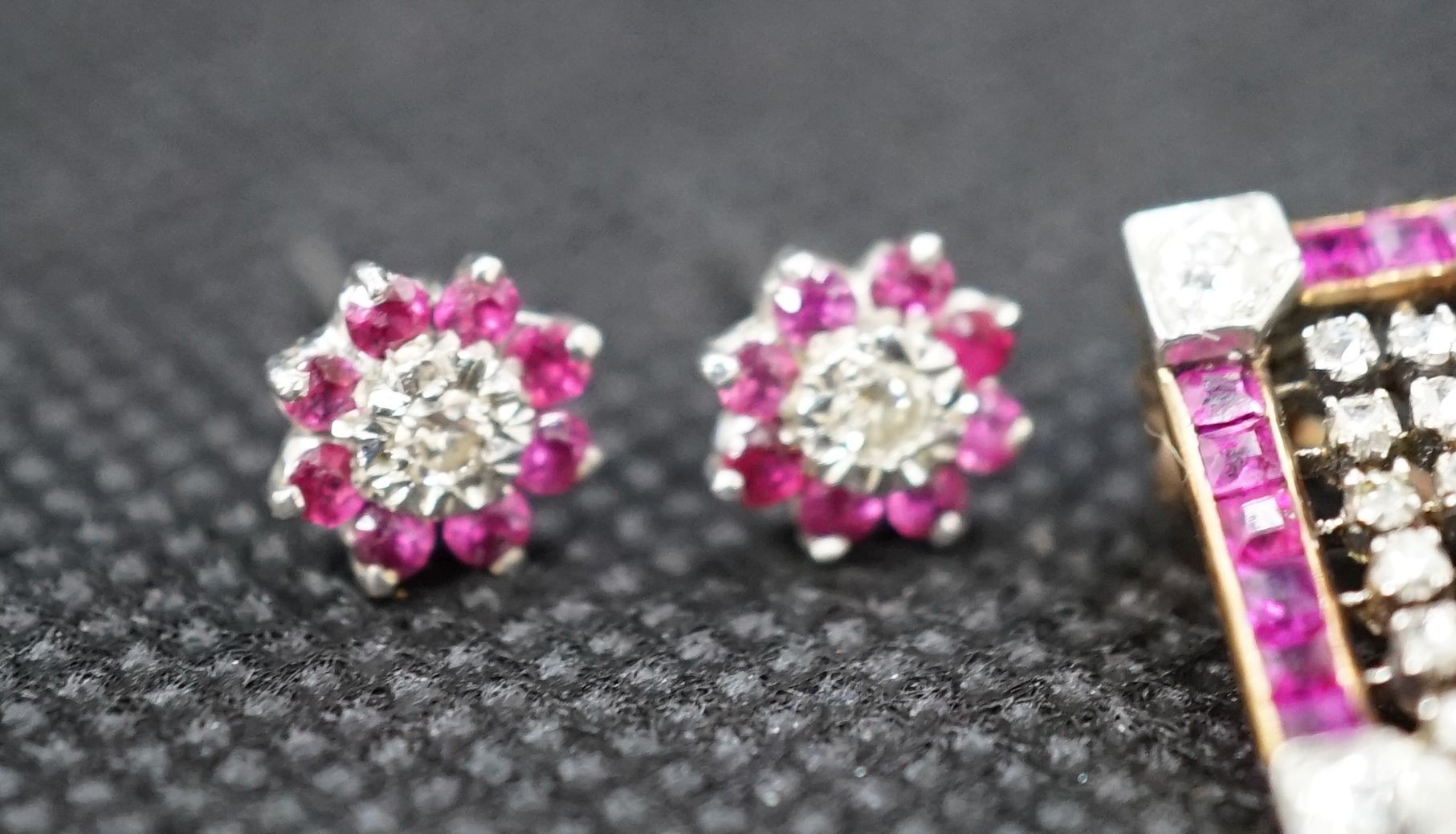An early 20th century pierced yellow metal, ruby and diamond cluster set square brooch, 17mm and a pair of white metal, ruby and diamond cluster flower head ear studs, gross weight 5.8 grams.